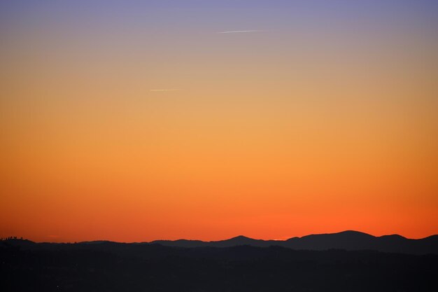 Scenic view of silhouette mountains against orange sky