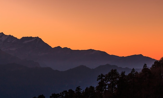 Photo scenic view of silhouette mountains against orange sky