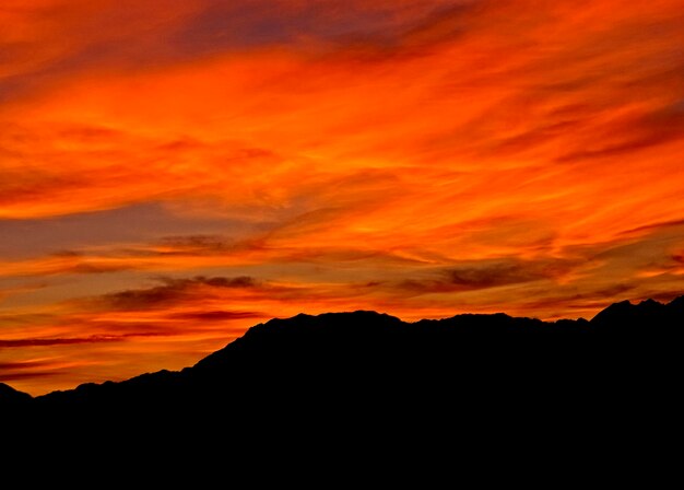 Scenic view of silhouette mountains against orange sky