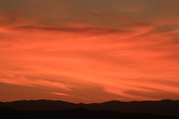 Scenic view of silhouette mountains against orange sky