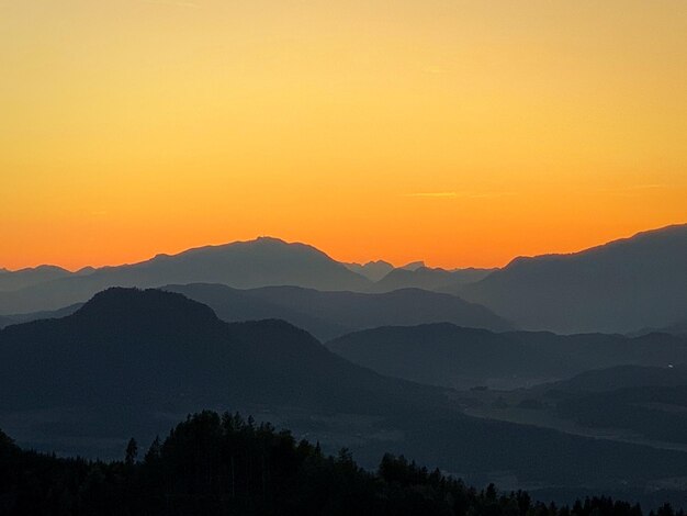 Photo scenic view of silhouette mountains against orange sky