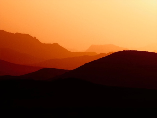 오렌지색 하늘 을 배경 으로 한 산 의 실루 의 풍경