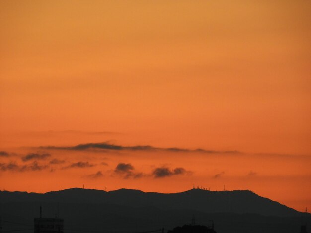 Scenic view of silhouette mountains against orange sky