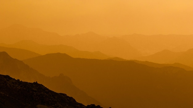 Photo scenic view of silhouette mountains against orange sky