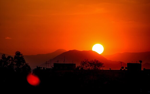 Scenic view of silhouette mountains against orange sky