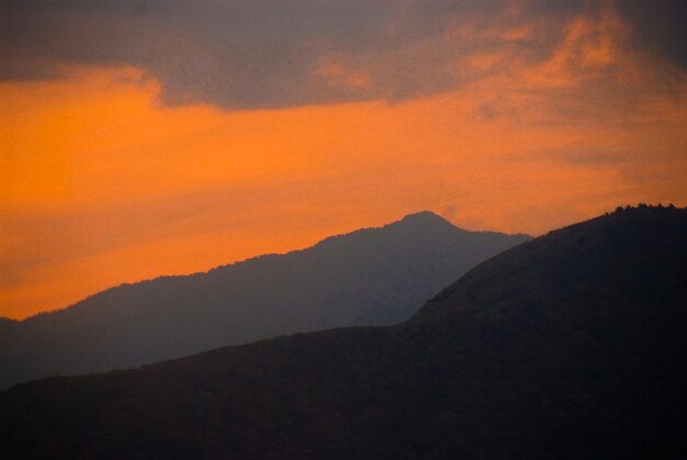 Scenic view of silhouette mountains against orange sky