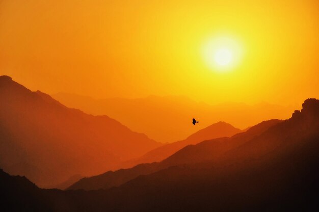 Scenic view of silhouette mountains against orange sky