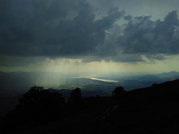 Scenic view of silhouette mountains against storm clouds