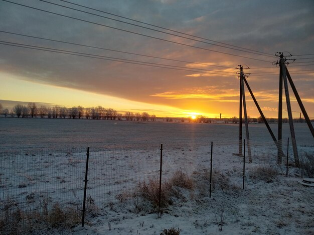 Scenic view of snow covered field against sky during sunset