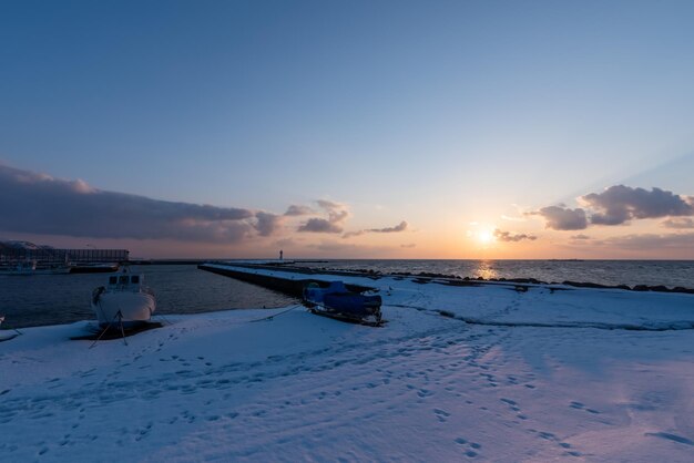 Photo scenic view of snow covered land against sky during sunset