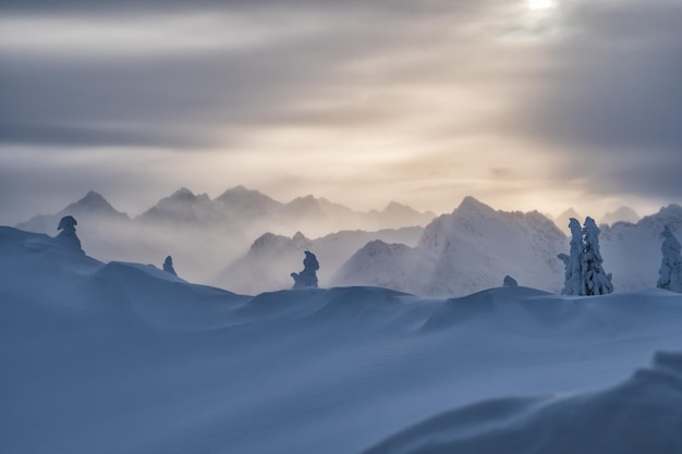 夕暮れの雲の空に照らされた雪に覆われた風景の景色
