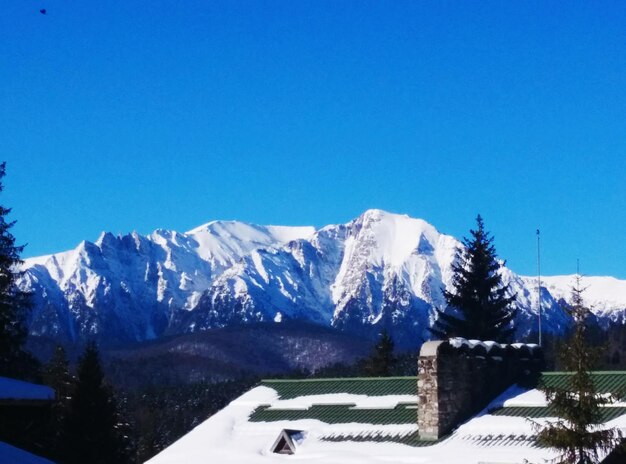 Scenic view of snow covered mountains against blue sky