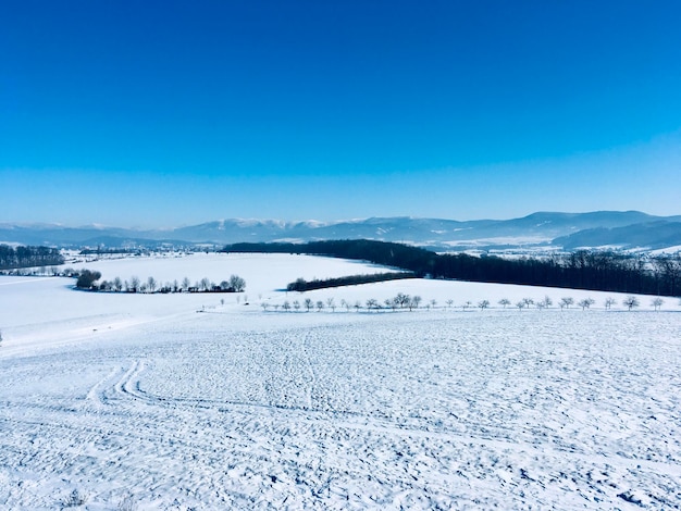 Scenic view of snow covered mountains against blue sky