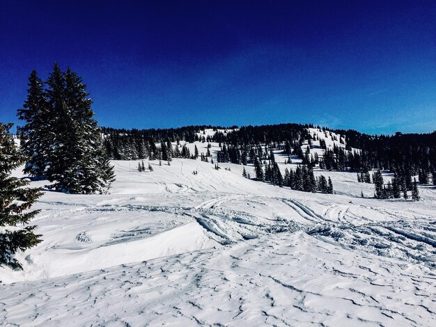 Scenic view of snow covered mountains against clear blue sky