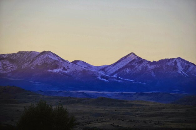 Scenic view of snow covered mountains against clear sky during sunset