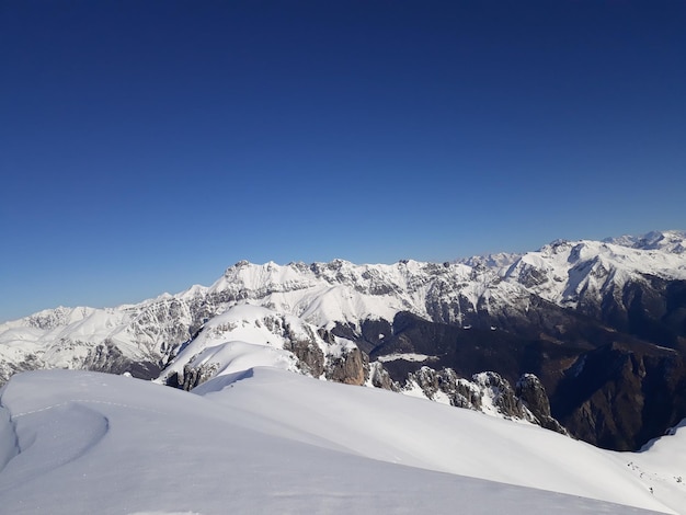 Foto vista panoramica delle montagne innevate contro un cielo blu limpido