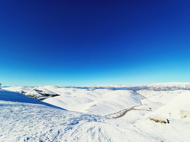 Scenic view of snowcapped mountains against clear blue sky