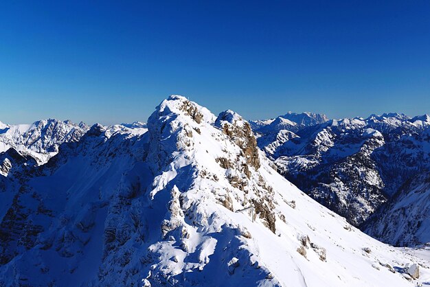 Scenic view of snowcapped mountains against clear blue sky