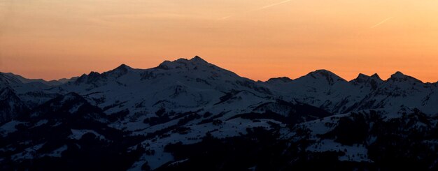 Photo scenic view of snowcapped mountains against sky during sunset