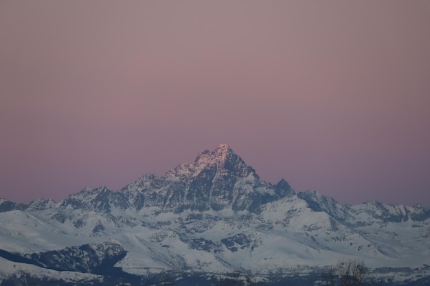 夕暮れ の 時 の 空 に 照らさ れ て いる 雪 に 覆わ れ た 山 の 景色