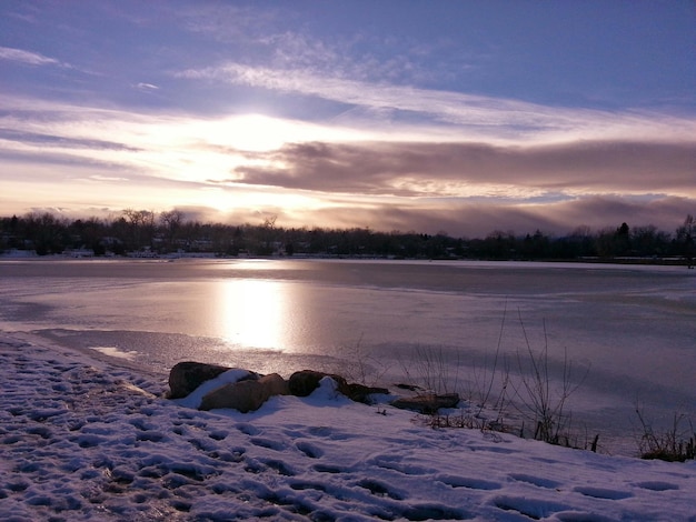 Photo scenic view of snowy field by frozen lake against cloudy sky