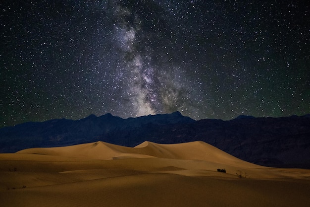 Photo scenic view of star field over desert landscape