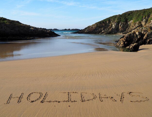 Photo scenic view of text on beach against sky