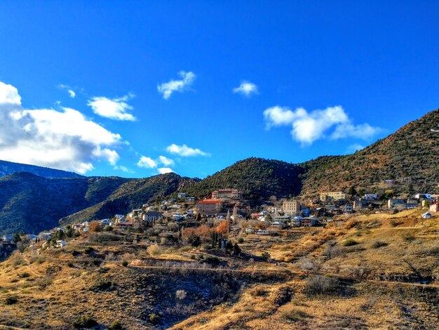 Scenic view of townscape and mountains against blue sky