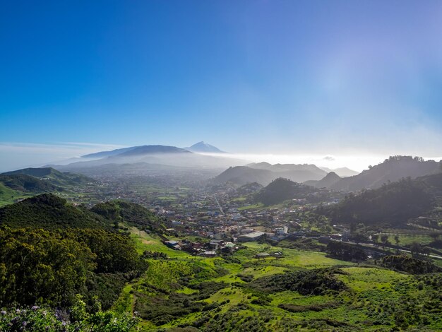 Scenic view of townscape and mountains against blue sky