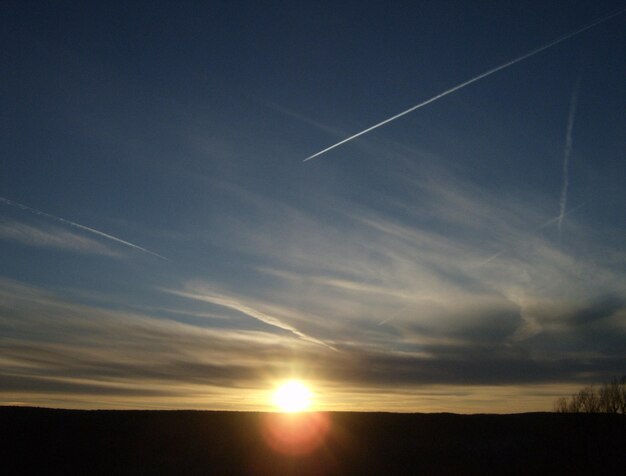 Scenic view of vapor trails in sky during sunset