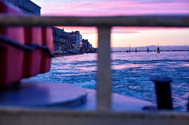 Photo scenic view of venetian lagoon against sky during sunset seen through railing