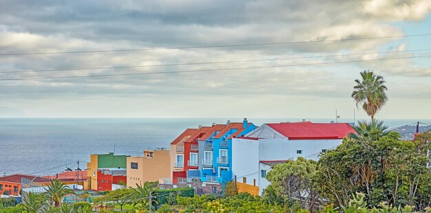 스페인 산타크루스 데 라 팔마(Santa Cruz de La Palma)의 활기찬 색상 주택 바다와 푸른 하늘과 복사 공간의 아름다운 전망 관광지의 기반 시설 건물에서 자라는 열대 야자수