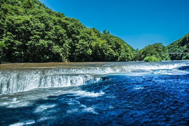 Photo scenic view of waterfall against clear blue sky