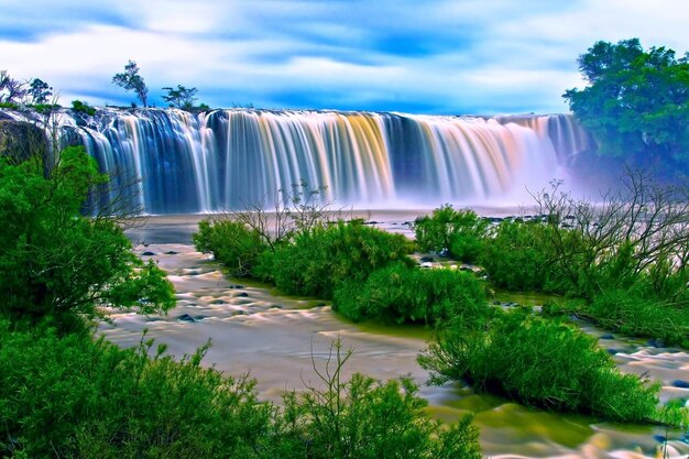 Scenic view of waterfall against cloudy sky