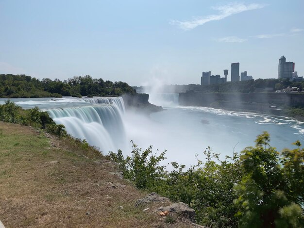 Photo scenic view of waterfall against sky in city