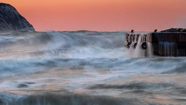 Scenic view of waterfall against sky during sunset