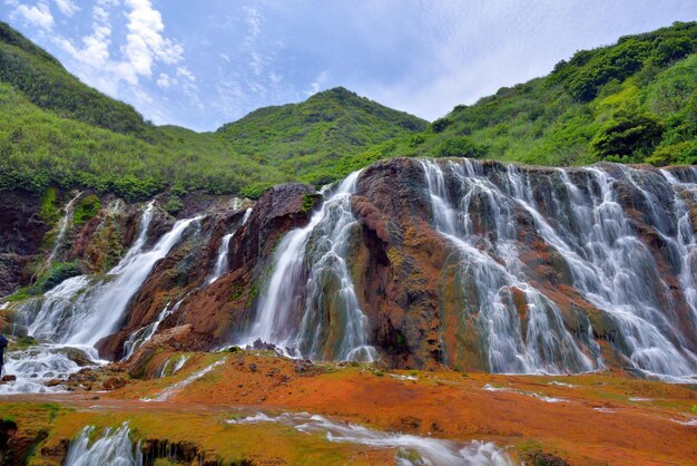 Scenic view of waterfall in forest against sky