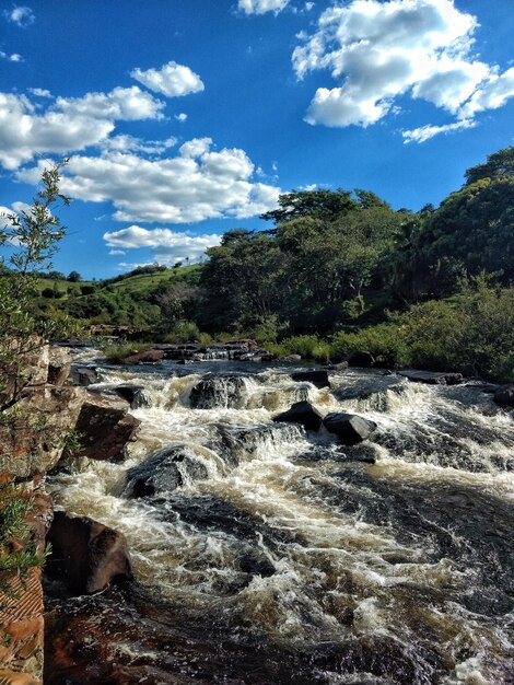 Scenic view of waterfall in forest against sky