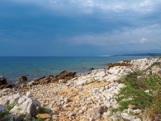 Scenic view of wild beach with white rocks at the sea against blue sky on on krk island croatia