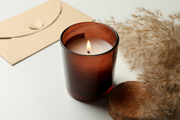 Scented candle, envelope and reed on white background