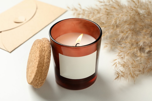 Scented candle, envelope and reed on white surface