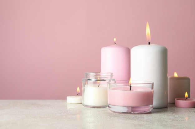 Ароматические свечи для отдыха на белом столе на розовом фоне