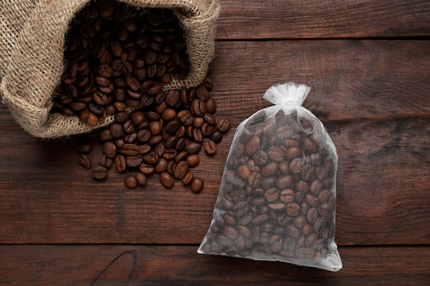 Scented sachet with coffee beans on wooden table flat lay