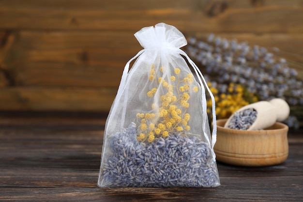 Scented sachet with dried flowers on wooden table closeup