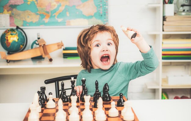 Schaakschool Zoon schaakt en lacht thuis Kleine slimme jongen die aan schaken denkt