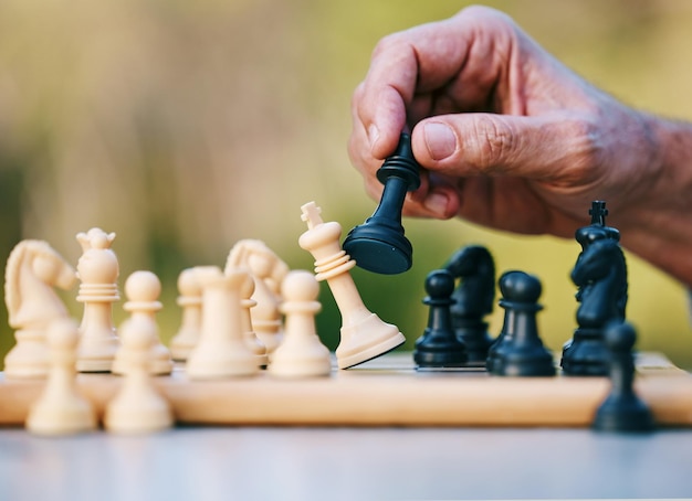 Foto schaakspel of hand met een koning op een bordspel met een winnende strategie in een toernooi buiten in de natuur schaakmat-mentaliteit of slimme man die speelt in een sportwedstrijd of probleemoplossende uitdaging