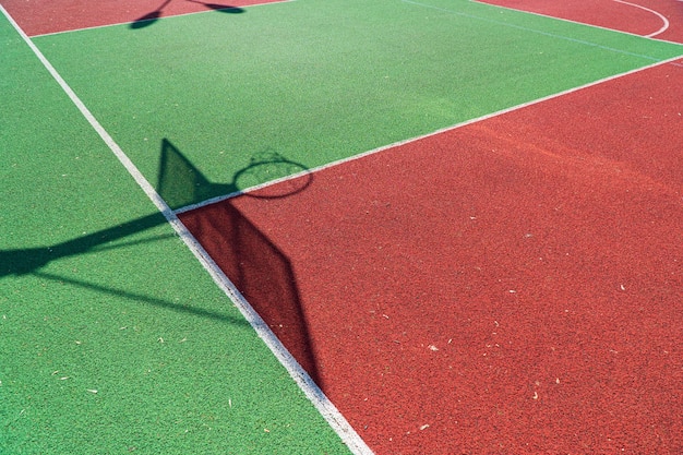 Schaduw van het rek met schild en basketbalring op basketbalveld Kleurrijke basketballijnen op een buitenbaan