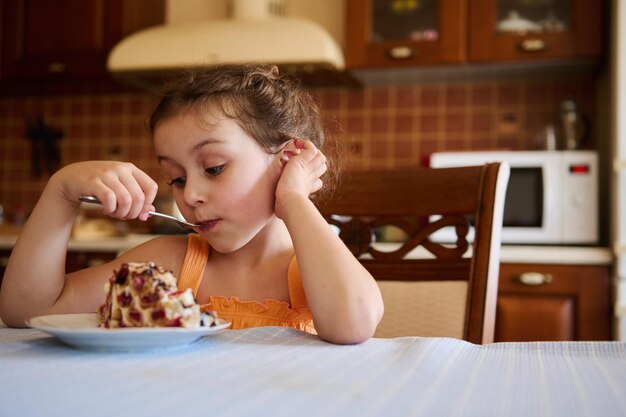 Schattig babymeisje dat een heerlijk zoet kersentaartdessert proeft in de keuken thuis