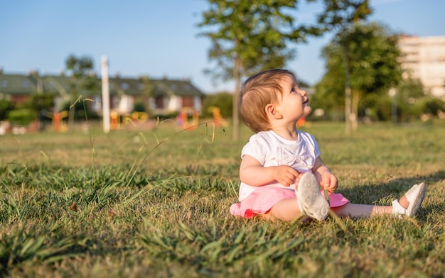 Schattig babymeisje spelen zittend op het graspark in een zonnige zomerdag