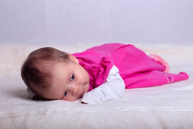 Schattig babymeisje van een maand oud in roze jurk ligt op een zachte deken